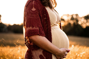 A pregnant person standing in the middle of a field