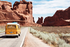 A yellow camping van driving across a desert scene