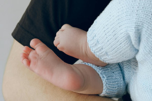 adult arms holding a baby wearing knitted wool pants